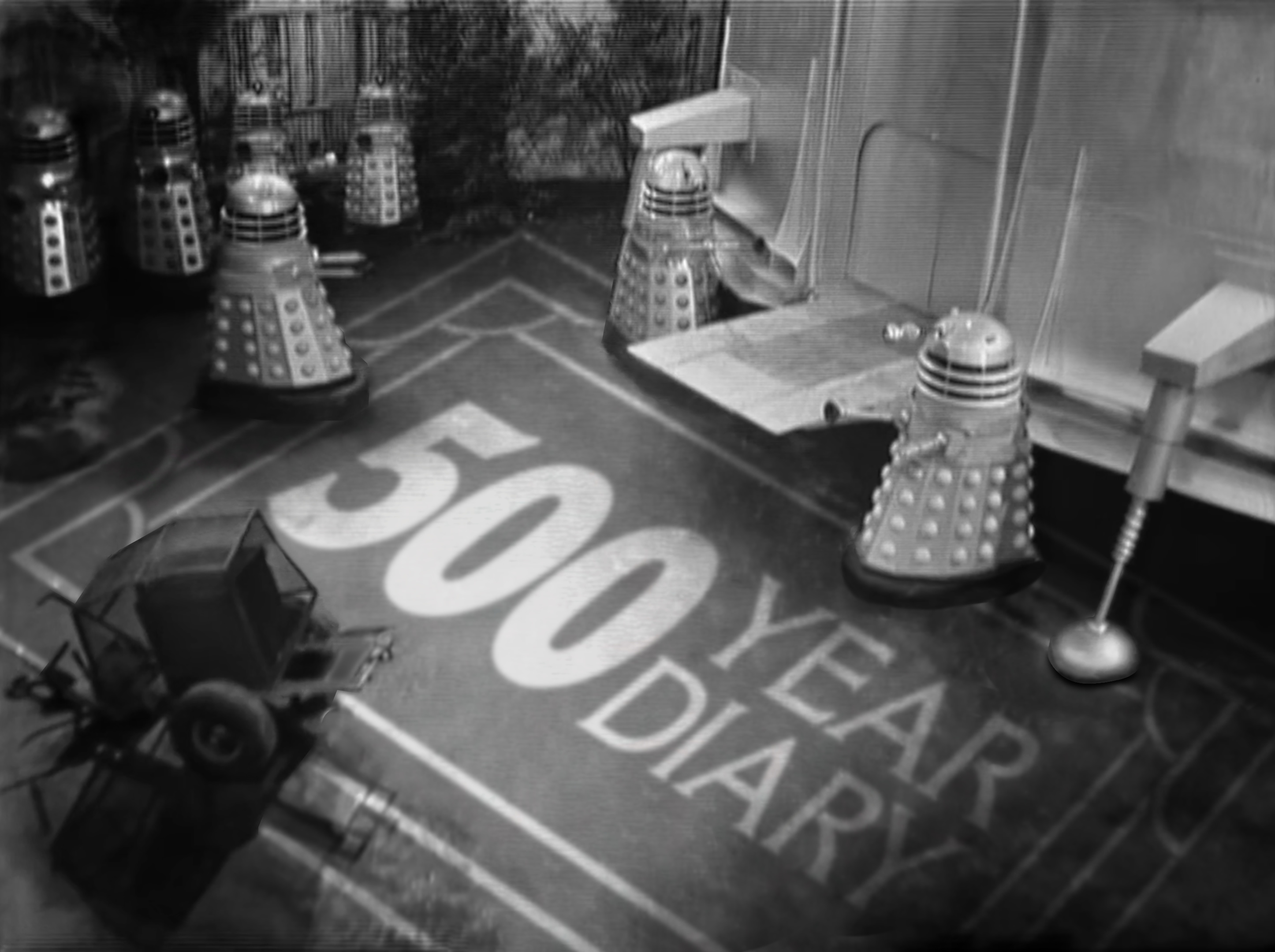 The Dalek saucer is parked in Sloan Square. We're looking at it from above: the entryway is surrounded by Daleks. On the ground, the 500 Year Diary logo is painted across the tarmac.